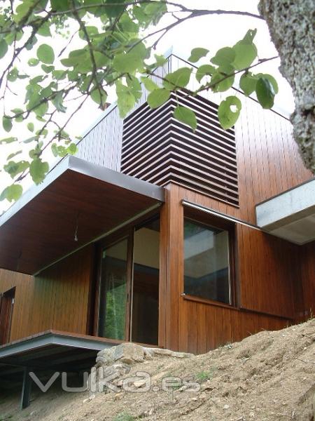 Casa con muros de carga de hormigón y estructura de hierro, revestida de madera, celosia