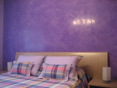 Estucado de cabecero en color morado y conjunto de cama a juego