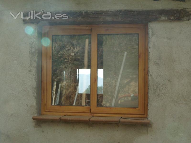 Ventana corredera, de aluminio imitacin madera, colocada en una casa de campo