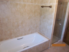 Banera y ducha con mampara en habitacion principal