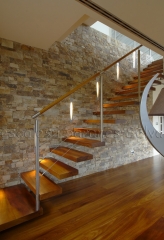 Escalera volada con peldanos de madera y barandilla de acero inoxidable con cables longitudinales