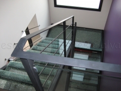 Escalera con estructura lateral en hierro y peldanos en cristal explosionado baranda de hierro