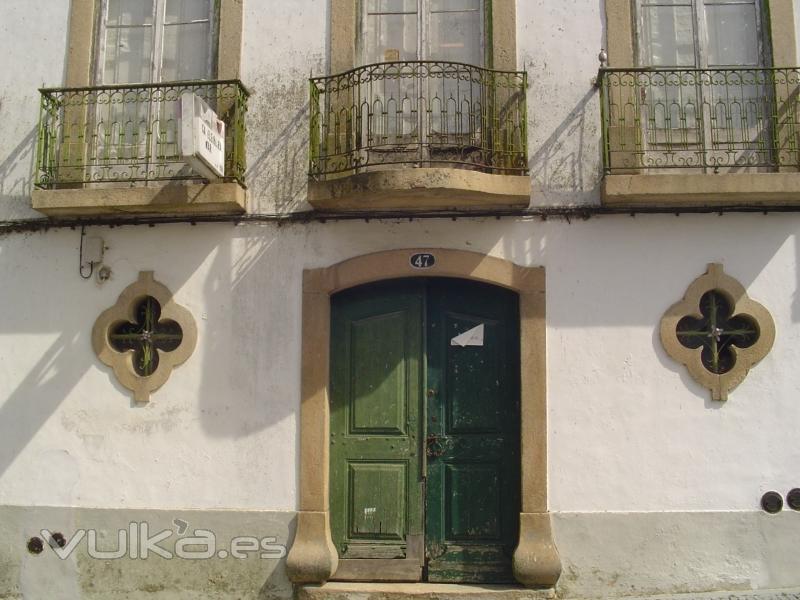 Unas ventanas de piedra muy peculiares y un verde precioso en el portón.