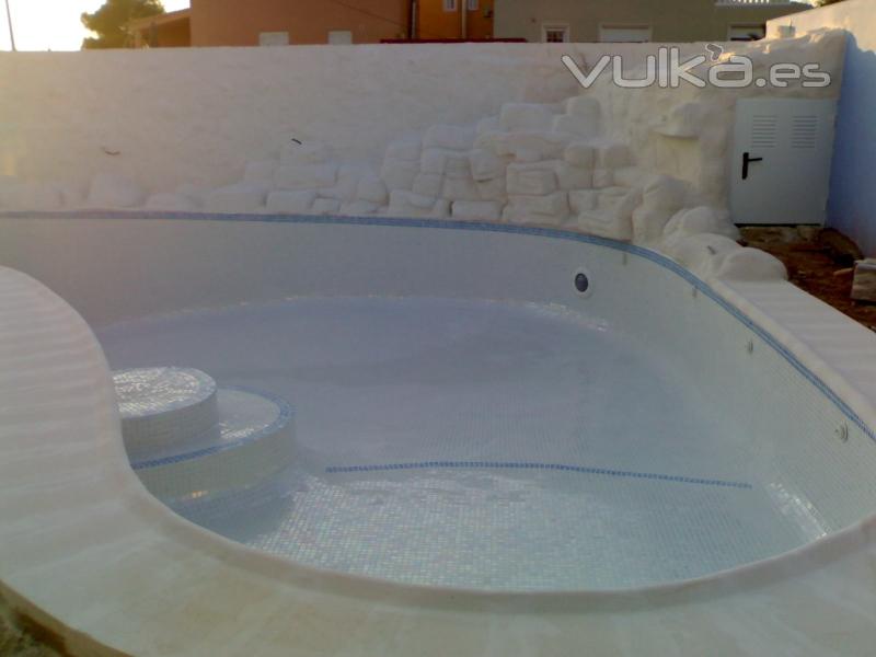 construccion de piscina con forma de rion y chapado con gresite blanco perla