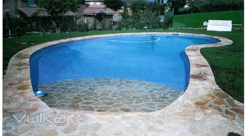 Piscina con entrada de playa en piedra natural.