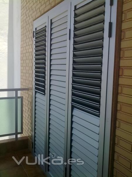 Puerta persiana de aluminio anodizado plata, de tres hojas abisagradas, lamas moviles.