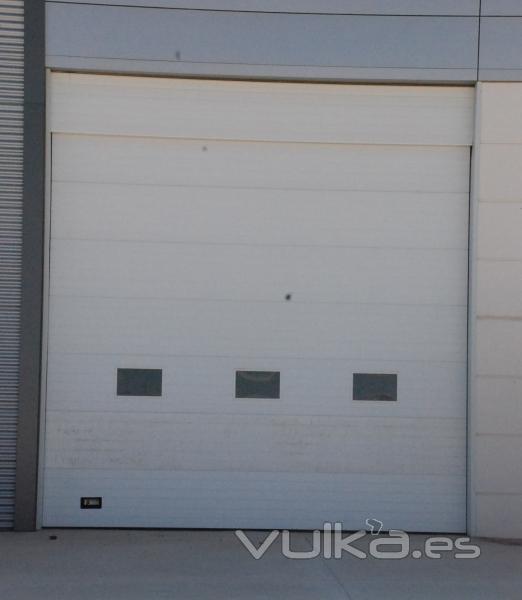 Puerta seccional industrial blanca con ventanillos