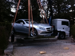 Camion grua descargando un mercedes para la realizacion de un evento en casa monico
