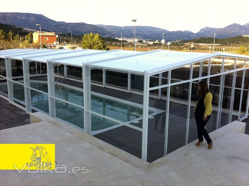 Es una cubierta de piscina telescpica de tres ngulos, sin guas en el suelo. La fachada puede ser 