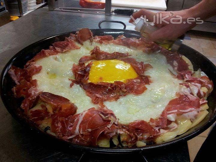 Huevo de avestruz sobre patata panadera con jamón ibérico y aceite de trufa