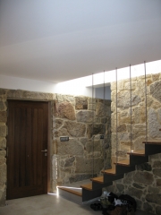 Reforma de una vivienda en cangas. escalera empotrada en el muro original