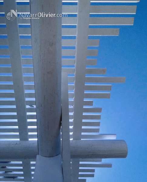 Pérgola de luz difusa con listones de madera tratada en autoclave con pilares en palo redondo