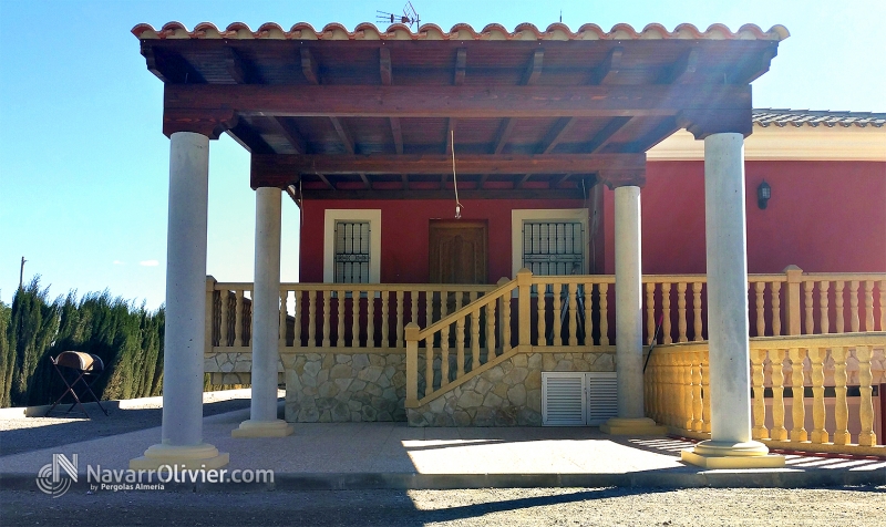 Pérgola adosada sobre pilares de cemento, con cubierta de teja