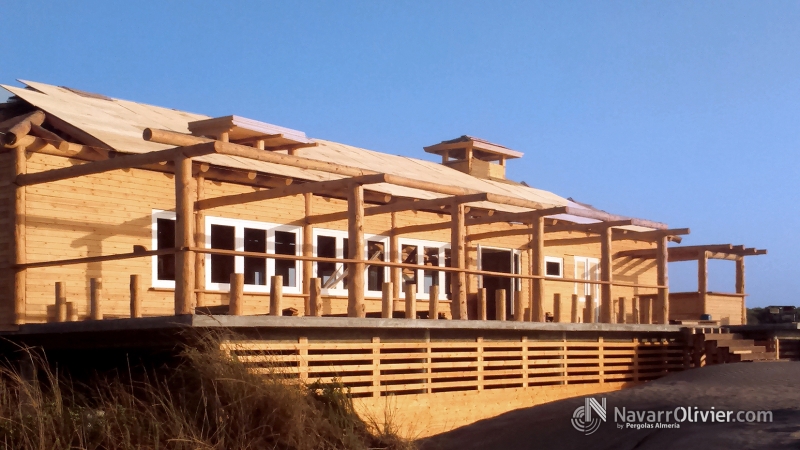 Chiringuito sobre plataforma elevada construido en troncos y madera natural.