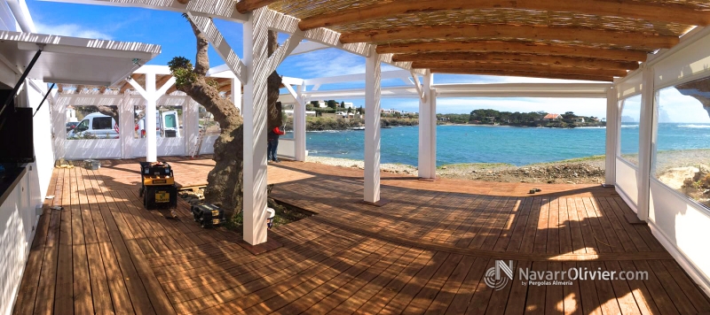 Terraza para chiringuito con suelo en tarima autoclave y pérgola en madera laminada y palo redondo