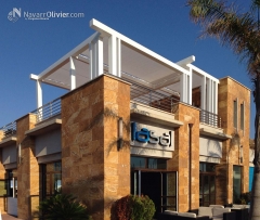 Pergola en madera laminada acabada en blanco con toldos en microperforado