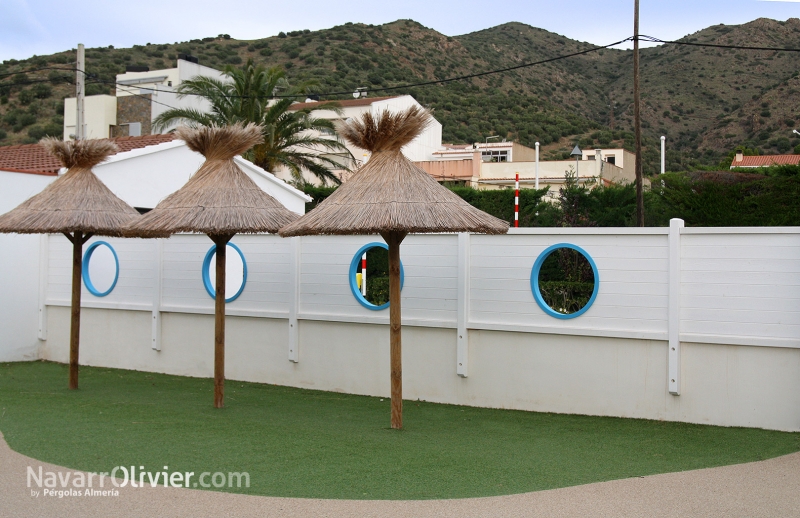 Muro de madera con aberturas circulares para camping Sant Miquel