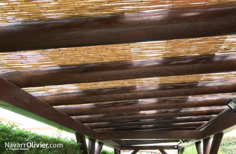 Pérgola con cubierta de cañizo construida en madera laminada y palo redondo