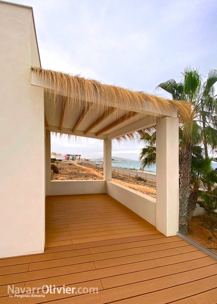 Pérgola de madera con remate decorativo en carritx natural y tarima sintética