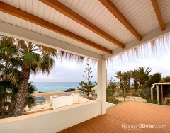 Terraza cubierta por pergola de madera con friso blanco con remate en carritx natural