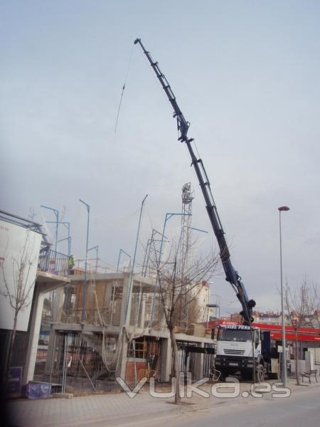 Camion-grua con jib y cabrestante a servicio de obra.