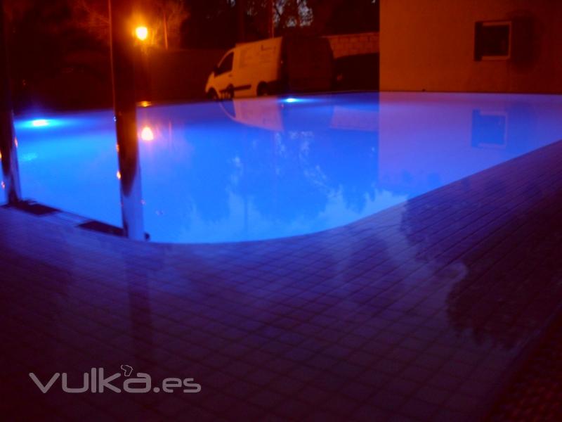 iluminacion con luces de leds en piscina desbordante con gresite blanco perla