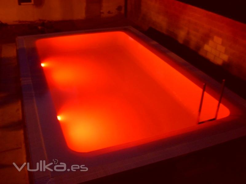 iluminacion con luces de leds en piscina desbordante con gresite blanco perla