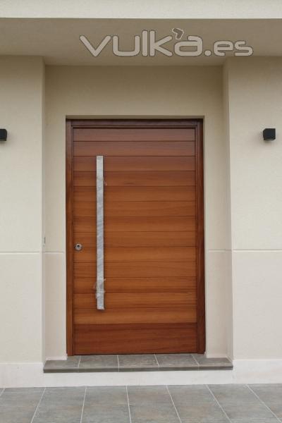 Puerta de 120 x 220 cm. en madera de Iroko y tirado r de acero inox.
