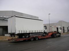 Camion rigido cargado en un semi-remolque porta-vehiculos