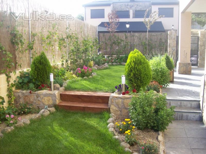 Diseo de jardn con csped antural y mezcla con jardineras de piedra y plantas.