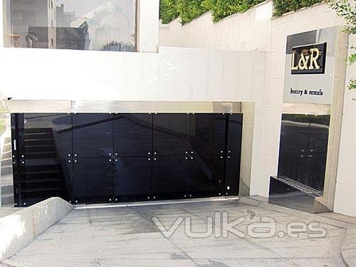 Puerta batiente automtica de dos hojas con vidrio de seguridad antimotn negro + inox.