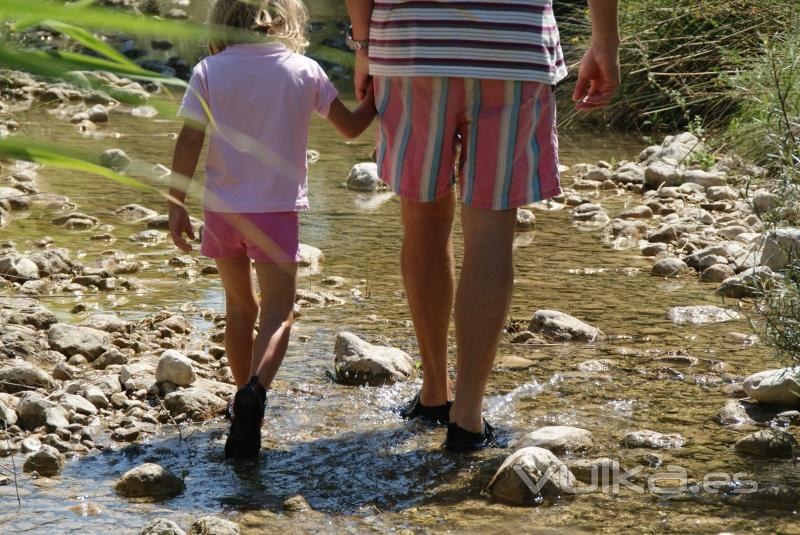 Padre e hija caminando libremente dentro de un rio con nuestro calzado