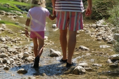 Padre e hija caminando libremente dentro de un rio con nuestro calzado
